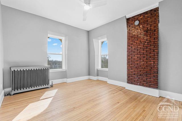 unfurnished room featuring radiator, ceiling fan, and light hardwood / wood-style floors