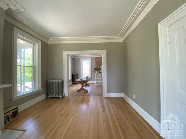 interior space featuring radiator heating unit, ornamental molding, and wood-type flooring