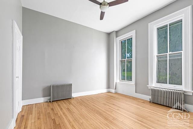 unfurnished room featuring ceiling fan, light hardwood / wood-style floors, and radiator