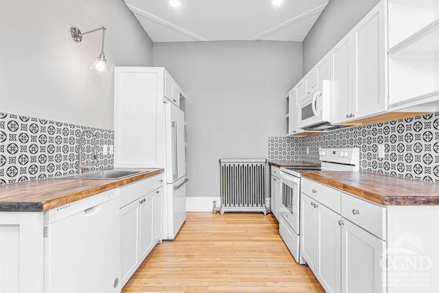 kitchen featuring butcher block countertops, white cabinets, and white appliances