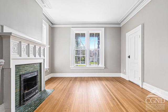 unfurnished living room featuring wood-type flooring and ornamental molding