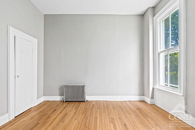 spare room with radiator heating unit and light wood-type flooring