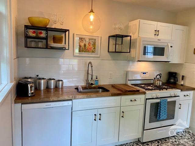 kitchen with white cabinetry, sink, tasteful backsplash, pendant lighting, and white appliances