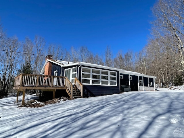 exterior space with stairs, a sunroom, a chimney, and a deck