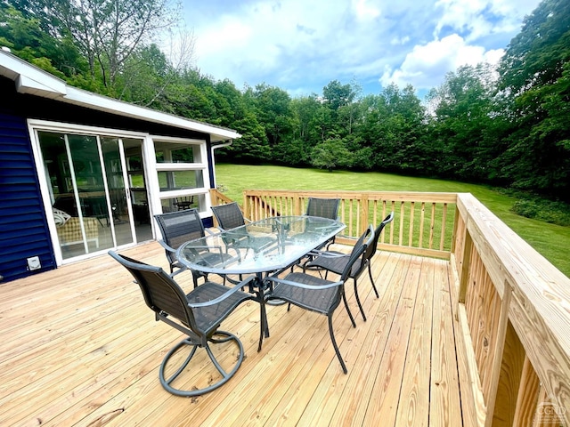 wooden terrace featuring outdoor dining space and a lawn
