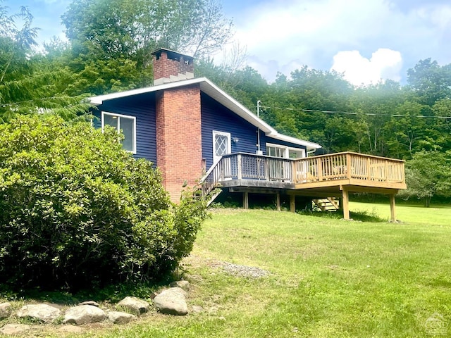 rear view of house featuring stairway, a lawn, a chimney, a deck, and a view of trees