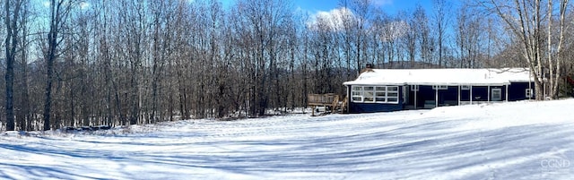 snow covered structure featuring a wooded view