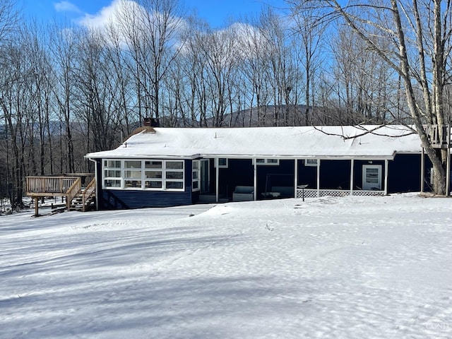 view of front of house featuring a chimney, a wooden deck, and a sunroom