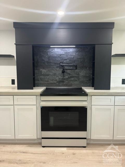 details with decorative backsplash, white cabinetry, light hardwood / wood-style floors, and white electric stove