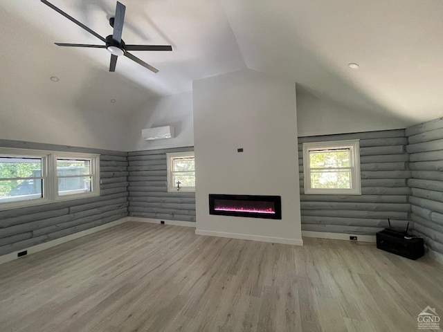 unfurnished living room featuring a wall mounted air conditioner, light hardwood / wood-style floors, a wealth of natural light, and lofted ceiling