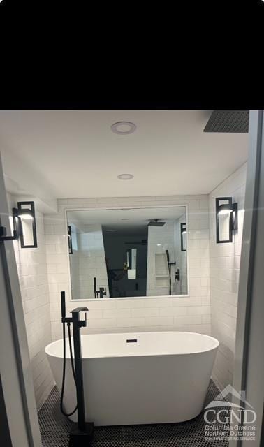 bathroom with tile patterned flooring, a tub to relax in, and tile walls