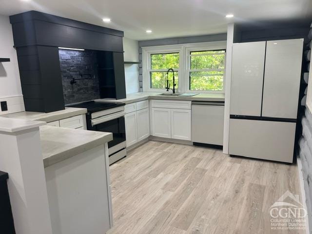 kitchen featuring stainless steel dishwasher, sink, electric range, light hardwood / wood-style floors, and white cabinetry