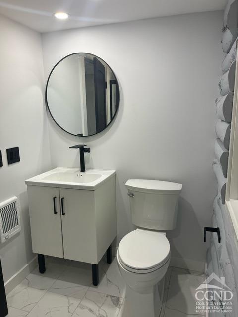 bathroom featuring heating unit, vanity, and toilet