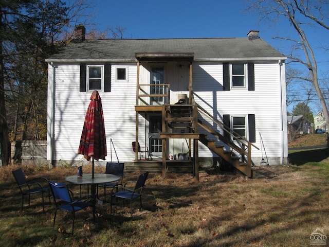 rear view of house featuring a wooden deck and a yard