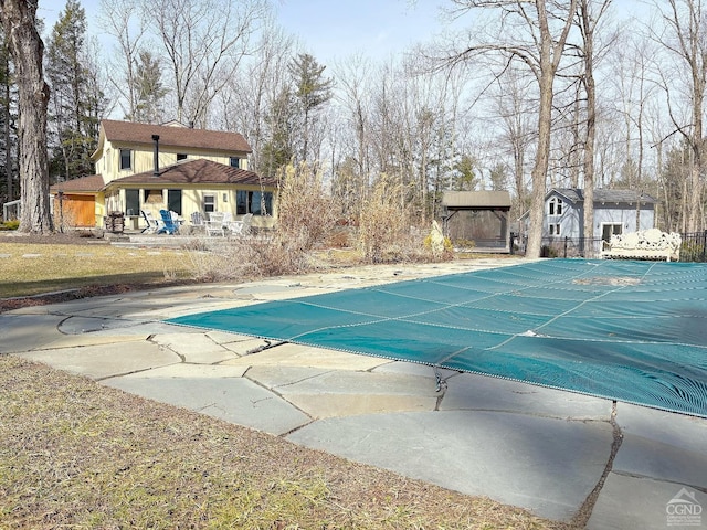 view of swimming pool with a covered pool, fence, and a patio area