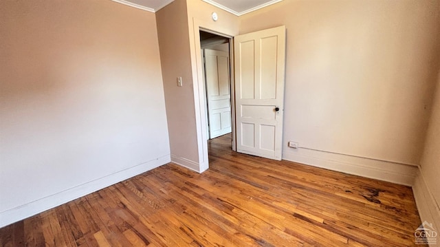 empty room with hardwood / wood-style floors and ornamental molding