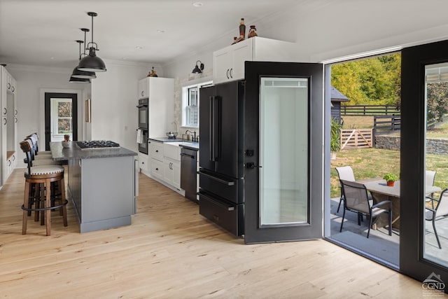 kitchen featuring white cabinets, pendant lighting, light hardwood / wood-style flooring, and a kitchen island