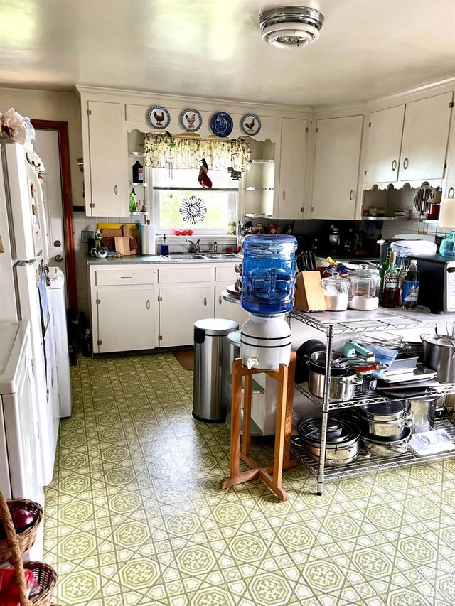 kitchen with white fridge, white cabinetry, and sink