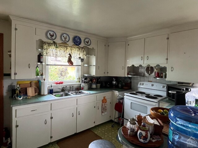 kitchen with electric range, backsplash, white cabinets, and sink