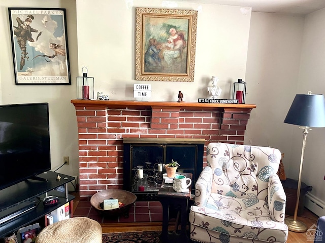 living room featuring hardwood / wood-style floors, a baseboard heating unit, and a brick fireplace