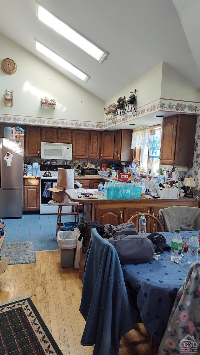 kitchen with high vaulted ceiling, white appliances, decorative backsplash, dark brown cabinets, and light wood-type flooring