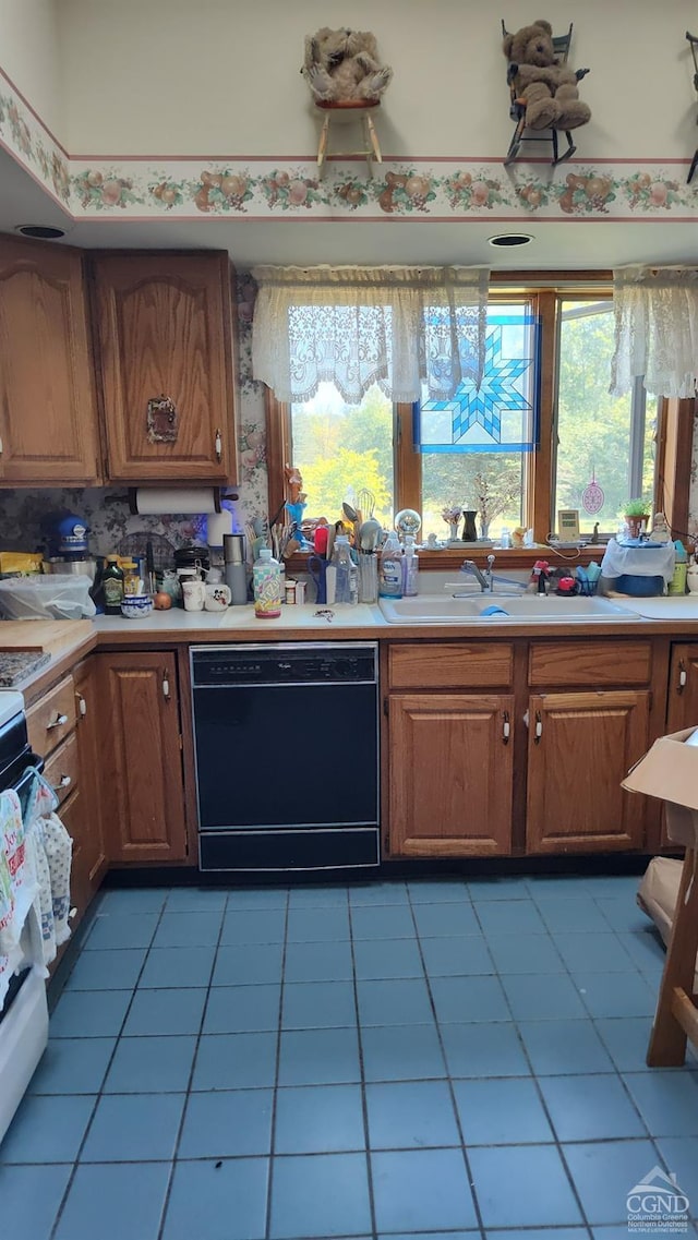 kitchen with dishwasher, stove, light tile patterned floors, and sink