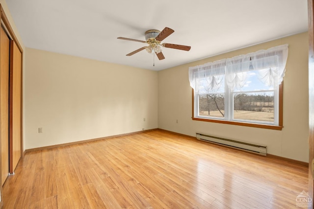 spare room with light wood finished floors, baseboards, a baseboard heating unit, and ceiling fan