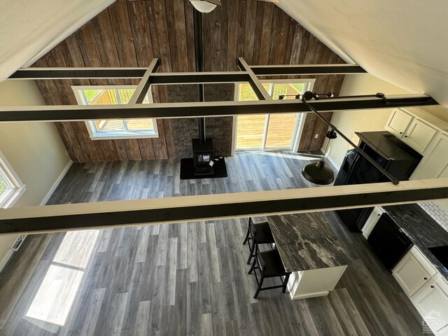 interior space with wood walls, a wood stove, white cabinets, a skylight, and dark hardwood / wood-style floors