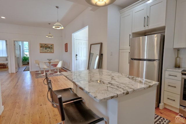 kitchen featuring a center island, light hardwood / wood-style floors, white cabinetry, and hanging light fixtures