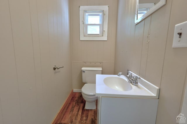 bathroom featuring wooden walls, toilet, vanity, and hardwood / wood-style flooring