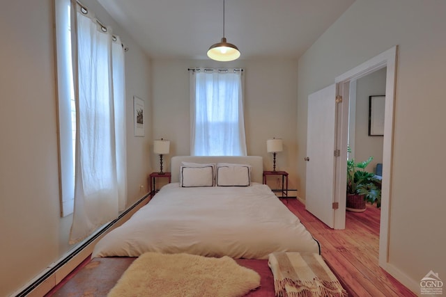 bedroom with light wood-type flooring and a baseboard heating unit