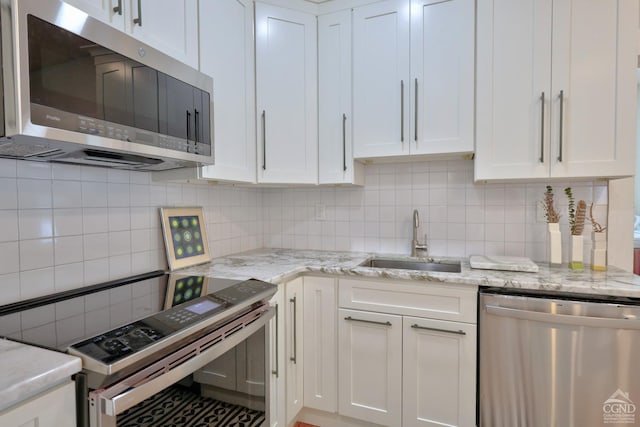 kitchen with appliances with stainless steel finishes, tasteful backsplash, white cabinetry, and sink