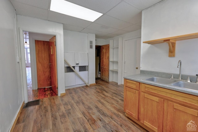 kitchen with a paneled ceiling, light wood-type flooring, and sink