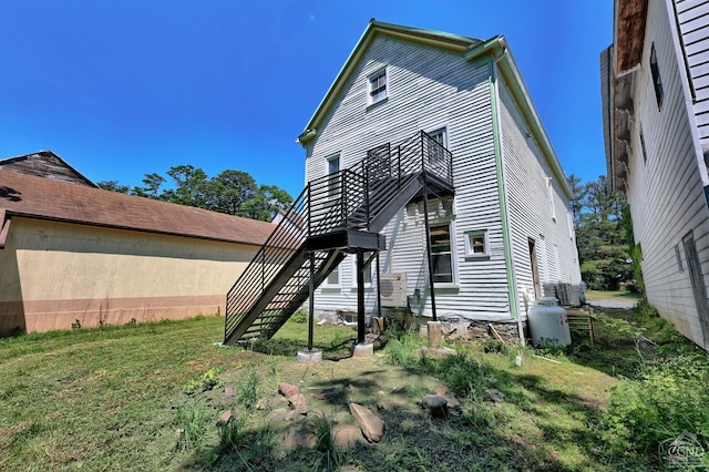 back of property featuring a balcony, cooling unit, and a lawn