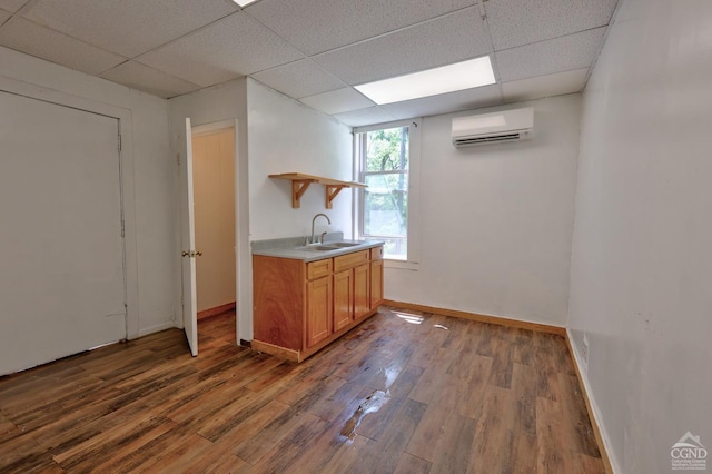 bar featuring a wall mounted air conditioner, a paneled ceiling, dark hardwood / wood-style floors, and sink