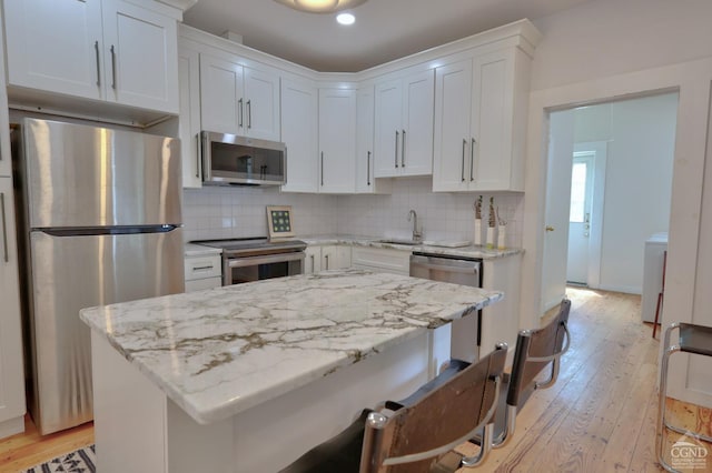 kitchen featuring white cabinets, light stone counters, light wood-type flooring, and appliances with stainless steel finishes