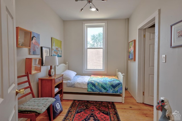 bedroom featuring light wood-type flooring and an inviting chandelier