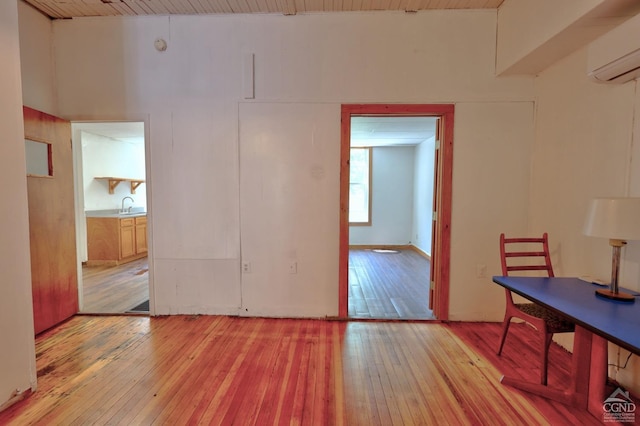 dining space with a wall mounted air conditioner, wood ceiling, sink, a high ceiling, and light hardwood / wood-style floors