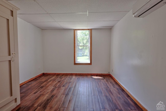 unfurnished room featuring a drop ceiling, dark hardwood / wood-style floors, and a wall mounted AC