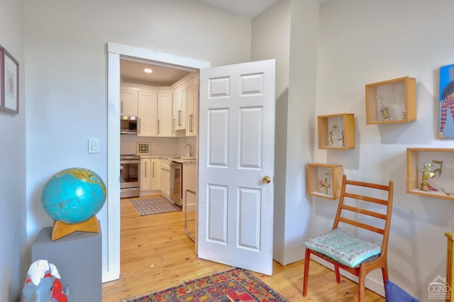 hallway with light hardwood / wood-style floors and sink