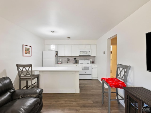 kitchen with white appliances, dark wood-type flooring, white cabinets, hanging light fixtures, and tasteful backsplash