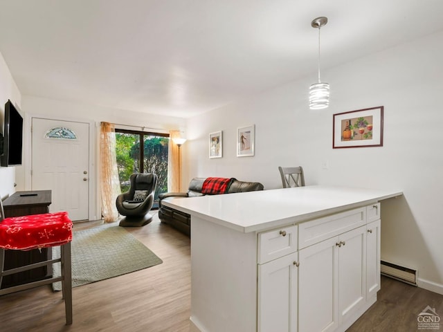 kitchen with decorative light fixtures, wood-type flooring, white cabinetry, and baseboard heating