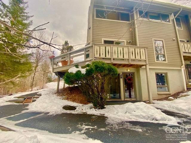 snow covered rear of property with a balcony