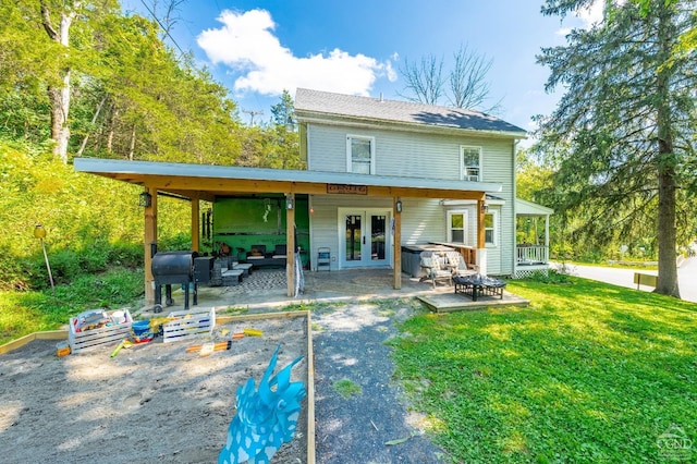 back of property featuring french doors, an outdoor fire pit, a yard, and a patio area