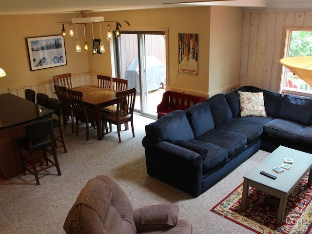 carpeted living room featuring wood walls and an inviting chandelier