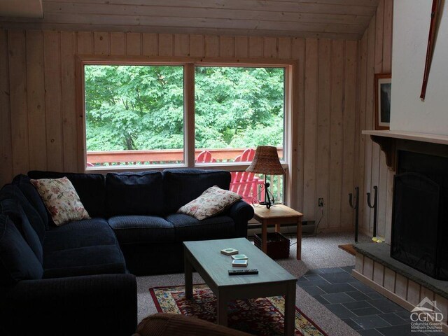 living area featuring a fireplace with raised hearth and wooden walls