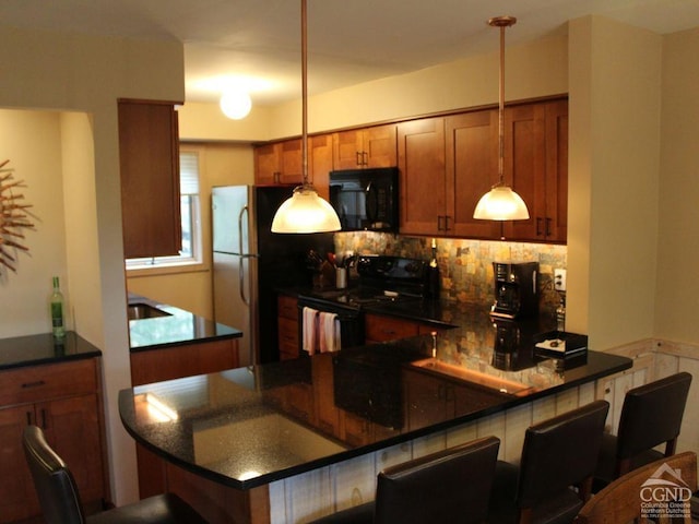 kitchen with brown cabinets, black appliances, dark countertops, a kitchen bar, and decorative light fixtures