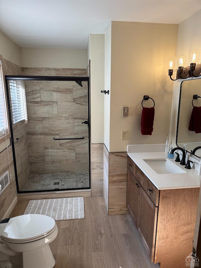 full bath with wood finished floors, a stall shower, vanity, and toilet