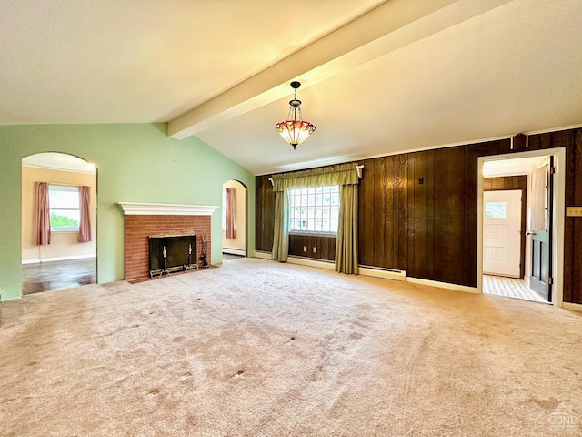 unfurnished living room featuring carpet, wood walls, a fireplace, and a wealth of natural light