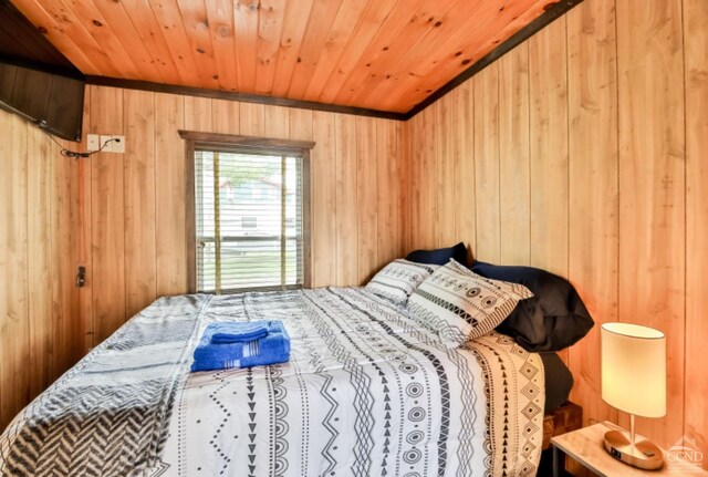 bedroom with wooden walls, crown molding, and wood ceiling